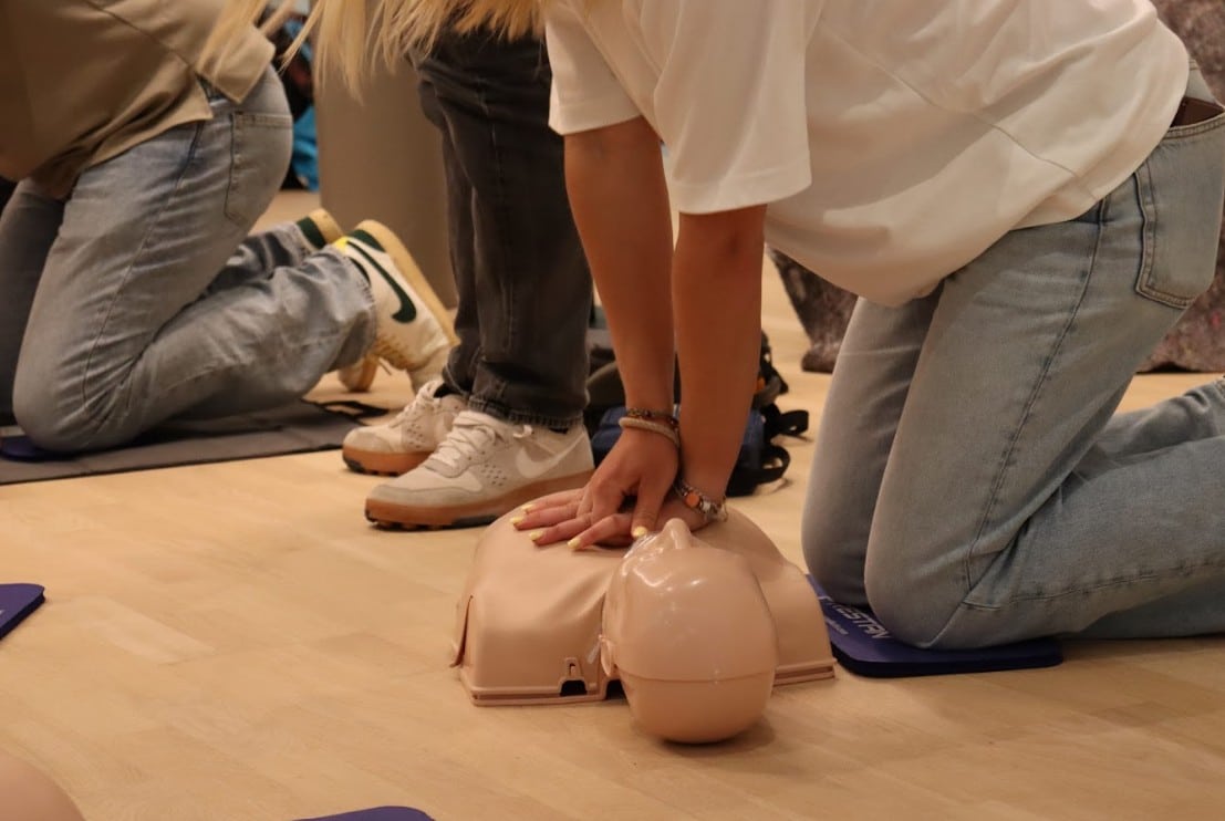 Cursisten oefenen borstcompressies op reanimatiepoppen tijdens een training