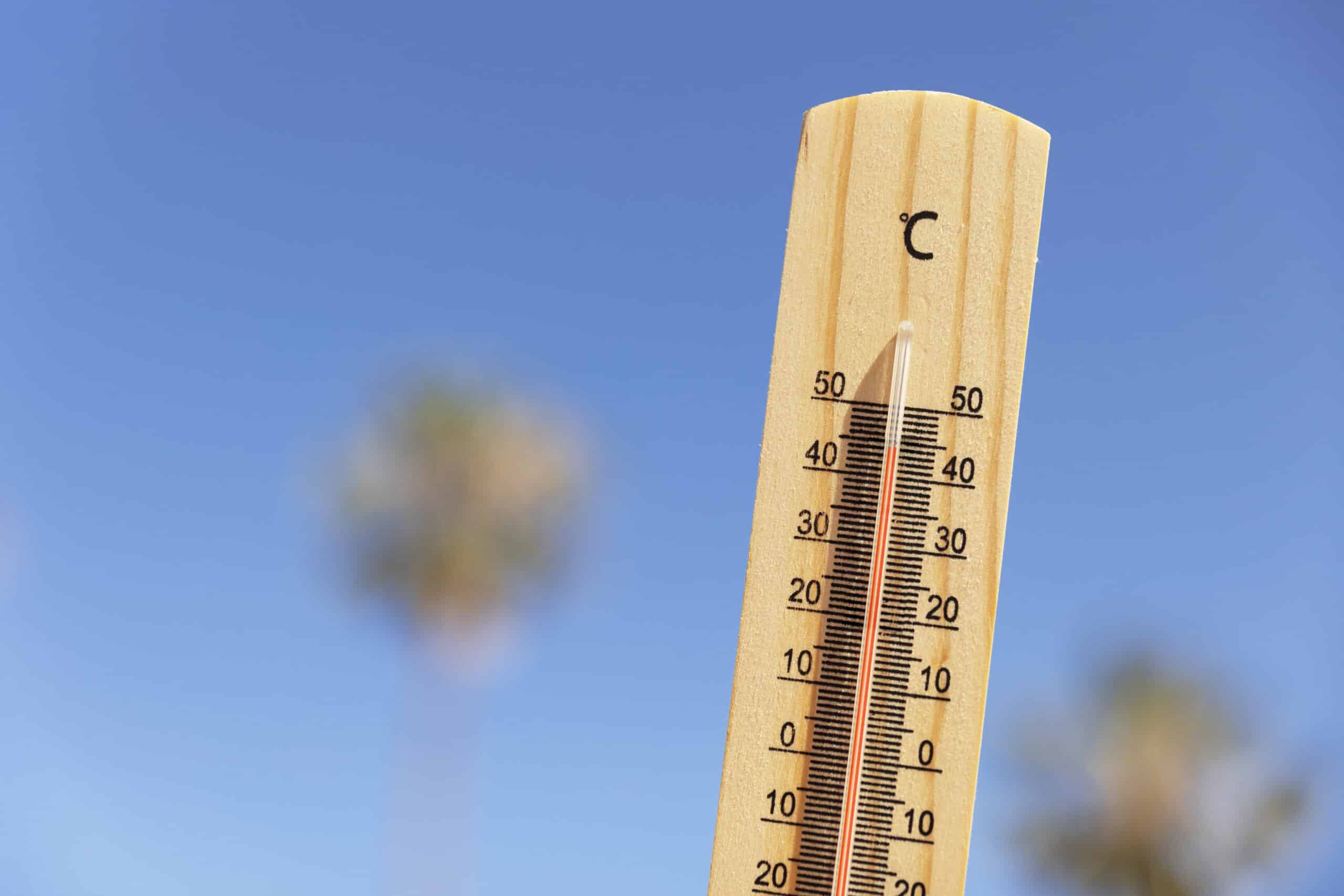 Houten thermometer tegen een strakblauwe lucht tijdens warm weer
